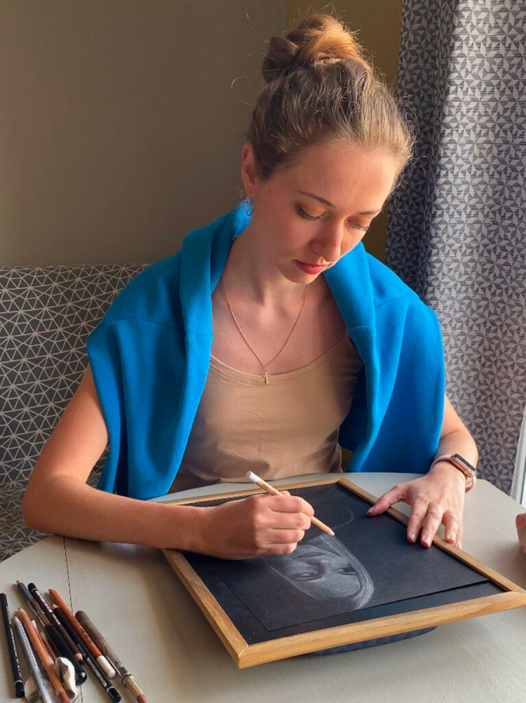 L’artiste Anneli de Anneli Studio dessine un portrait à la table avec des pastels.