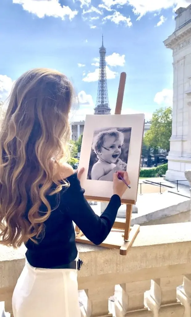 L’artiste Anneli avec un portrait au crayon devant la tour Eiffel